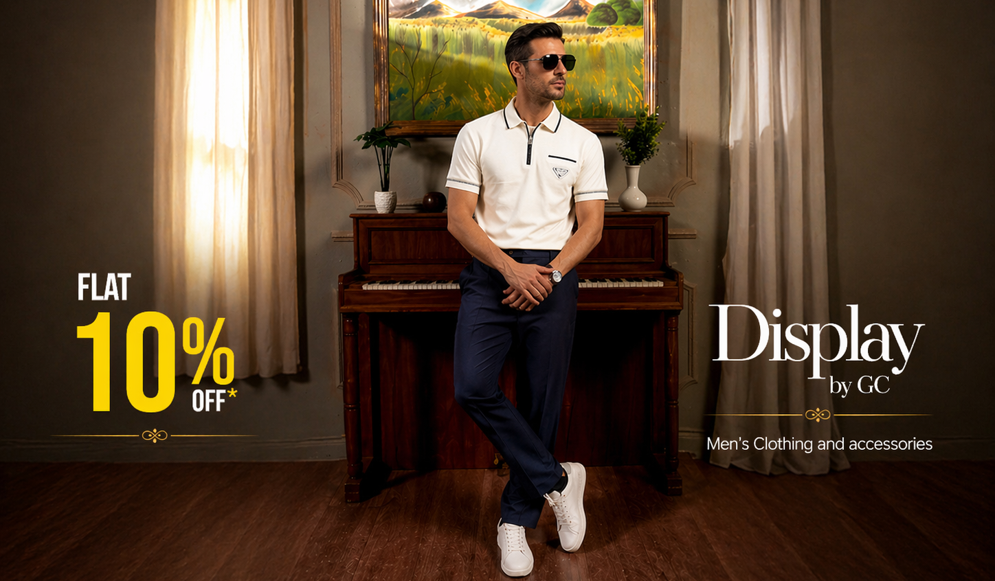 Man sitting on a piano in a room with a painting, wearing a white shirt and dark pants. Display by GC advertisement.